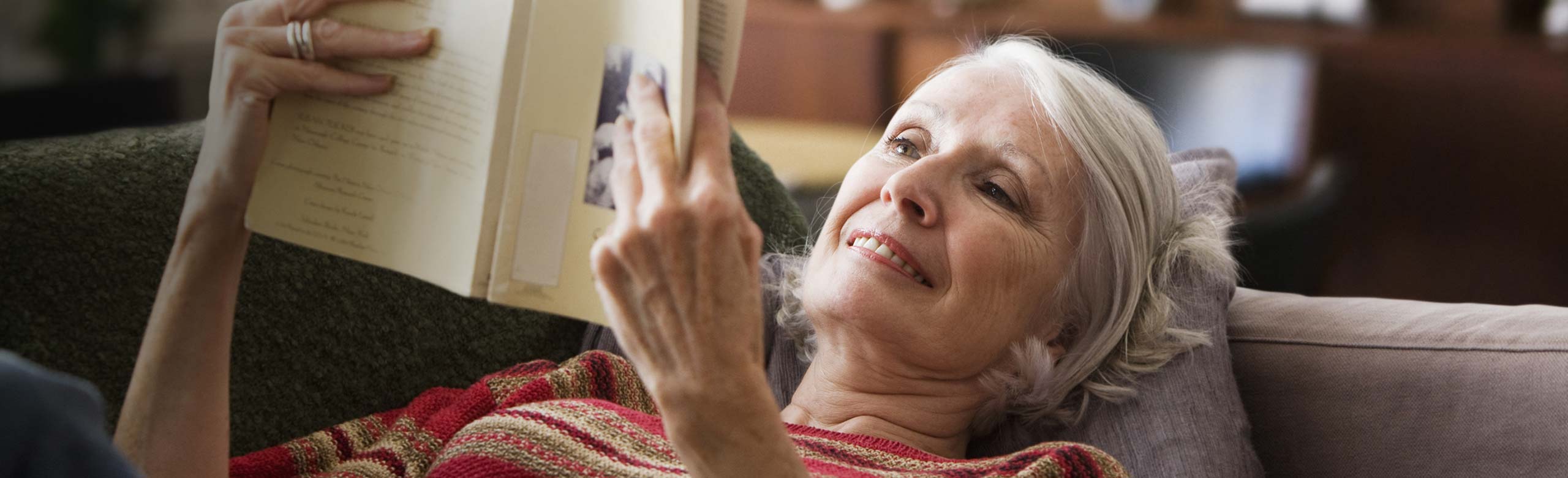 Woman laying on couch reading book