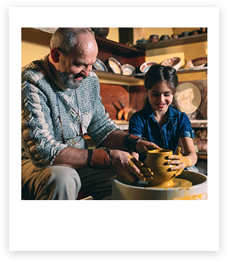 Man working on a pottery wheel with a child